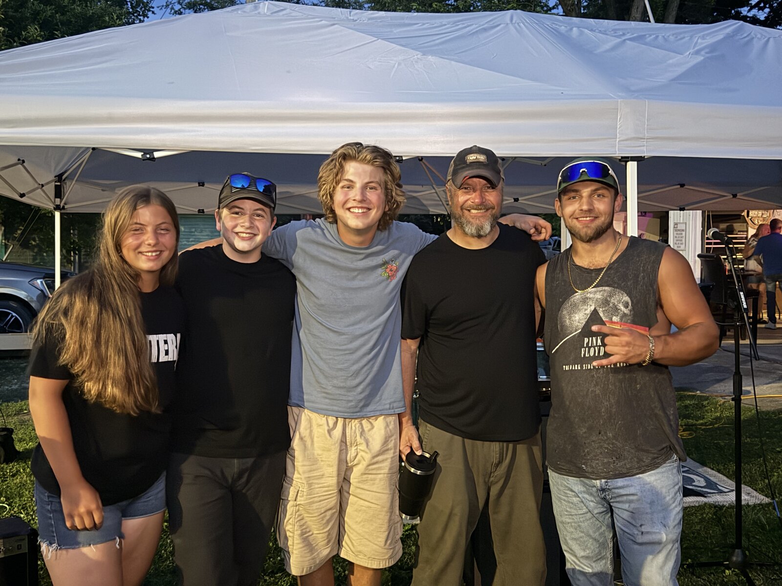 Five people posing together at an outdoor music event